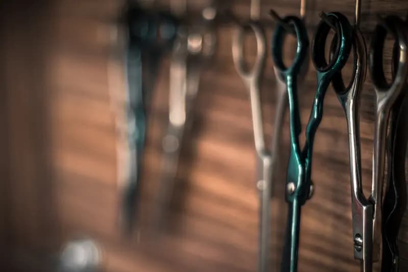 Tesouras de barbeiro penduradas numa parede de madeira